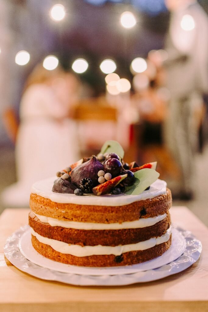 Naked-style cake topped with berries in an outdoor nighttime setting, perfect for elegant celebrations.