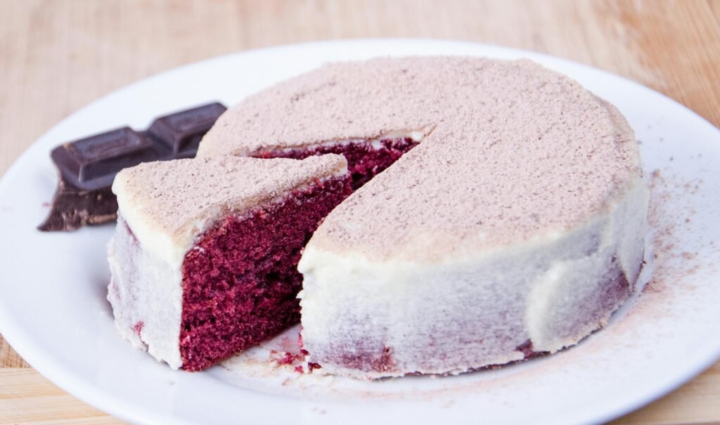 Sliced red velvet cake with cream cheese frosting on a white plate, perfect for dessert lovers.